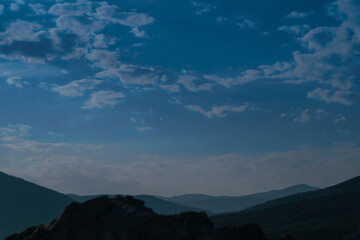 Pre-dawn night cloudy sky over mountains