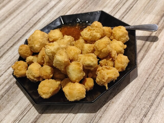 Crispy fried tofu served with sauce. Crispy fried tofu served with chili sauce on a black plate. Know the crispy tofu served at the cafe.