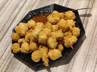 Crispy fried tofu served with sauce. Crispy fried tofu served with chili sauce on a black plate. Know the crispy tofu served at the cafe.