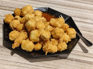 Crispy fried tofu served with sauce. Crispy fried tofu served with chili sauce on a black plate. Know the crispy tofu served at the cafe.