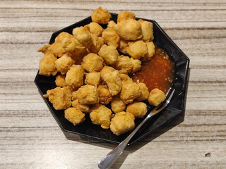 Crispy fried tofu served with sauce. Crispy fried tofu served with chili sauce on a black plate. Know the crispy tofu served at the cafe.
