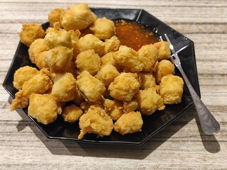 Crispy fried tofu served with sauce. Crispy fried tofu served with chili sauce on a black plate. Know the crispy tofu served at the cafe.