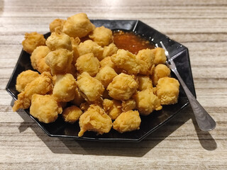 Crispy fried tofu served with sauce. Crispy fried tofu served with chili sauce on a black plate. Know the crispy tofu served at the cafe.