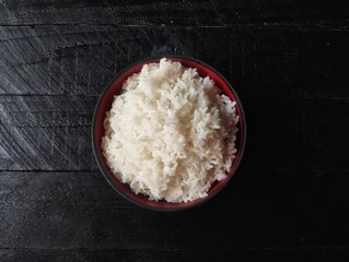 Nasi putih or white rice in bowl with black wooden table background, Flat lay 