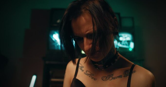 Portrait of strange tattooed woman looking at laptop display, work with PC. Female hacker or it programmer developing new software for cybersecurity, frustrated female person with piercing and tattoo