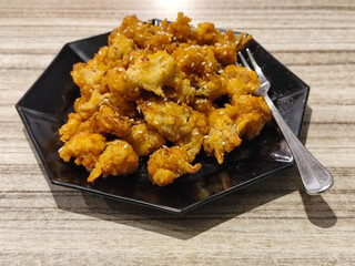 Crispy broccoli with chili sauce served on a black plate. Crispy broccoli with chili sauce served on a black plate, served in a cafe.