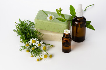 Chamomile oil in glass bottle and soap bars with flowers on white background
