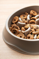 Dry dog food in a slow feeder bowl placed on a wooden surface