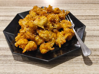 Crispy broccoli with chili sauce served on a black plate. Crispy broccoli with chili sauce served on a black plate, served in a cafe.