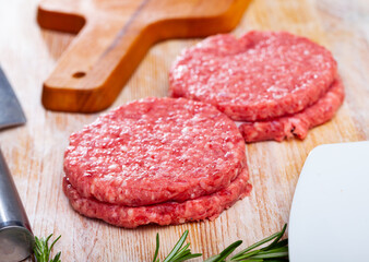 Close up of raw burger cutlet from pork on wooden table, nobody