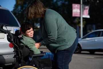 Mother taking care of her son with disability in a wheelchair outdoors