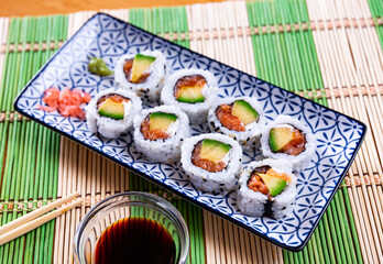 Uramaki roll with salmon, avocado and cream cheese, served with soy sauce..