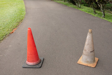 Two traffic cones placed on a closed road, serving as a barrier to restrict access and indicate a...