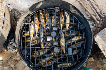 Fresh hot smoked salmon on traditional African oven grill for sales and preservation.