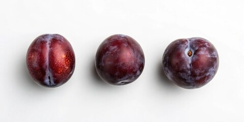 Obraz premium A trio of plums with a shiny surface, emphasizing their rich hues and appealing form on a white background.