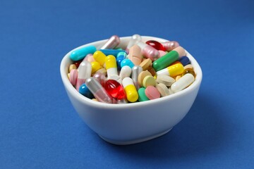 Various pills in a bowl on a blue background