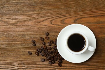 Cup of coffee with fresh coffee beans on wooden background