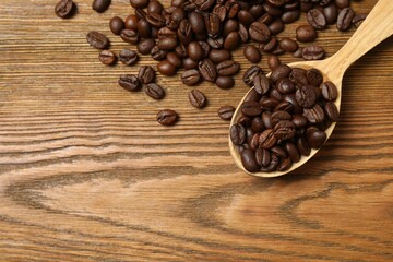 Fresh coffee beans in spoon on wooden background