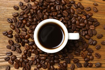 Cup of coffee with fresh coffee beans on wooden background