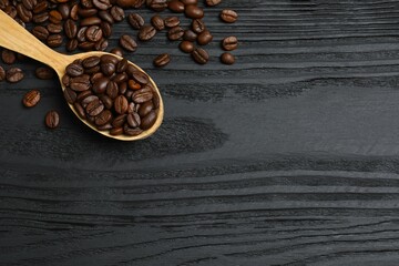 Fresh coffee beans in spoon on wooden background