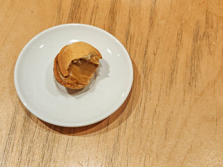 Halves of tasty walnut-shaped cookies with boiled condensed milk on the wooden table. White plate. Space for text.