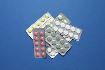 Pills in blister packs on blue background, close up
