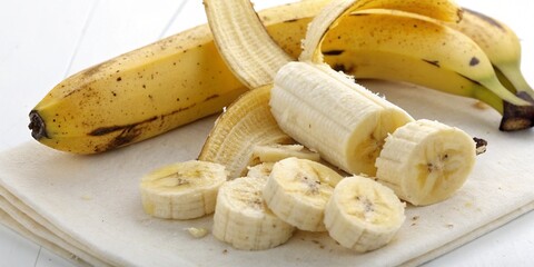 Sliced bananas on a cutting board, highlighting their creamy texture and freshness alongside whole bananas.