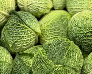 Fresh raw heads of Savoy cabbage on a greengrocers stall at a market