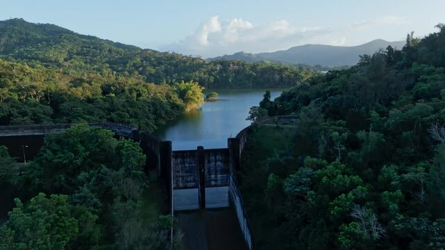 Aerial approaching shot of Hatillo Dam with picturesque seascape landscape of Dominican Republic. Tranquil and peaceful scenery with mountains at sunset. Wide shot.