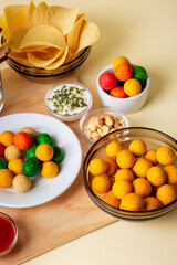 Different snacks such as chips, salted nuts, wasabi nuts on wooden desk on beige background.
