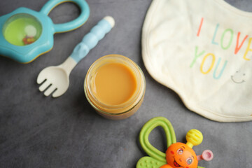 Homemade baby food jar beside feeding supplies on a table