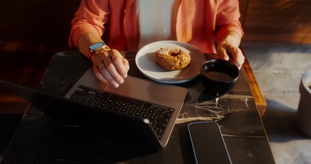 A man uses a laptop while sitting at a table in a cafe, close-up of a man's hands, no face