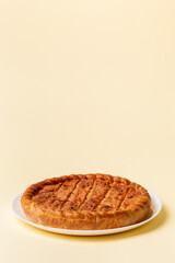 Tasty sweet pie on a white ceramic plate on beige background.