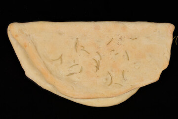 A rustic, folded focaccia bread, seasoned with herbs, is presented on a dark background, showcasing...