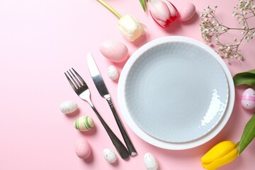 Easter decor concept. Top view photo of colorful eggs in a plate with knife and fork on pastel background