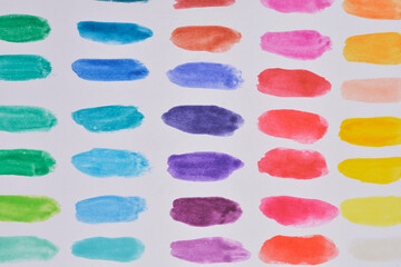 A close-up, top-down shot of numerous colorful watercolor swatches arranged in a grid pattern on...