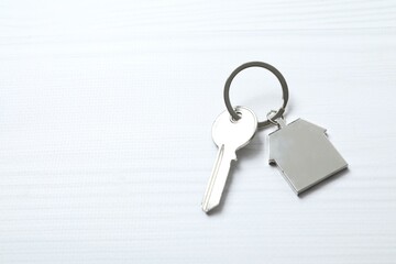 Metallic key with keychain in shape of house on white background