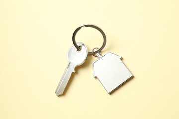 Metallic key with keychain in shape of house on color background
