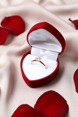 Beautiful shiny gold engagement ring with large diamond gemstone in a rich red velvet box on silk...