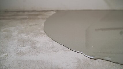 Pouring self-leveling concrete onto a rough surface, creating a smooth and even floor ideal for...