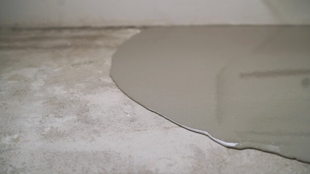 Pouring self-leveling concrete onto a rough surface, creating a smooth and even floor ideal for construction and renovation projects