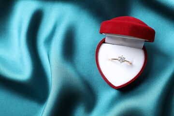Beautiful shiny gold engagement ring with large diamond gemstone in a rich red velvet box on silk...