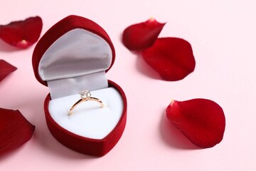 Beautiful shiny gold engagement ring with large diamond gemstone in a rich red velvet box with red...