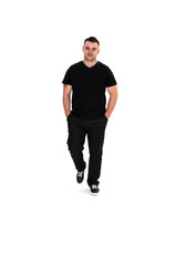 Fototapeta premium A handsome dark-haired man in a black T-shirt, trousers and sneakers on a white background
