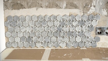 Tiler installing hexagonal marble tiles on bathroom wall using tile spacers