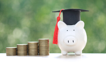 Graduation hat on piggy and stack of coins money on natural green background, Saving money for education concept