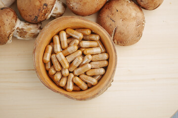 Mushroom supplements arranged in a wooden bowl with fresh mushrooms