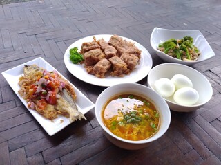 spicy fried fish, fried tofu and boiled egg on wooden table