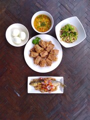 spicy fried fish, fried tofu and boiled egg on wooden table