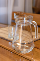 An empty pitcher on the table. Glass tableware for drinking.
